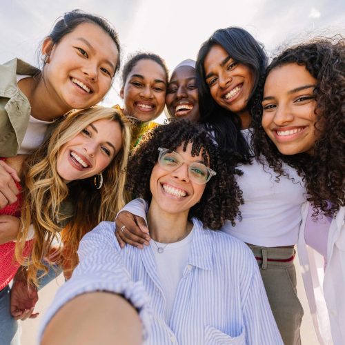 Diverse group of happy young female friends having fun taking selfie portrait together outdoors. Female friendship and youth concept.